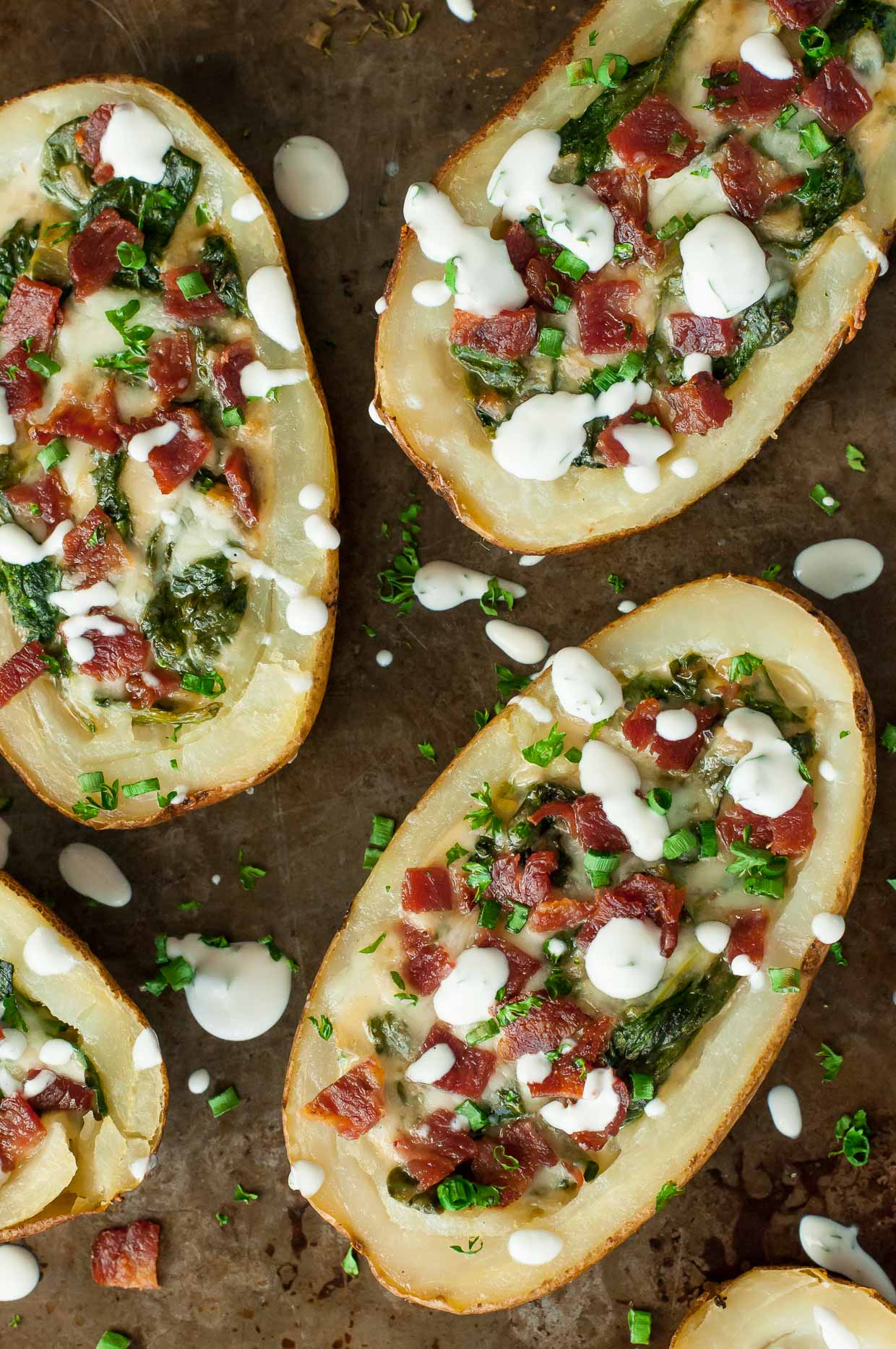 Creamy spinach artichoke dip and crispy loaded baked potato skins join forces, resulting in the ultimate party appetizer! We LOVE these loaded spinach artichoke potato skins!