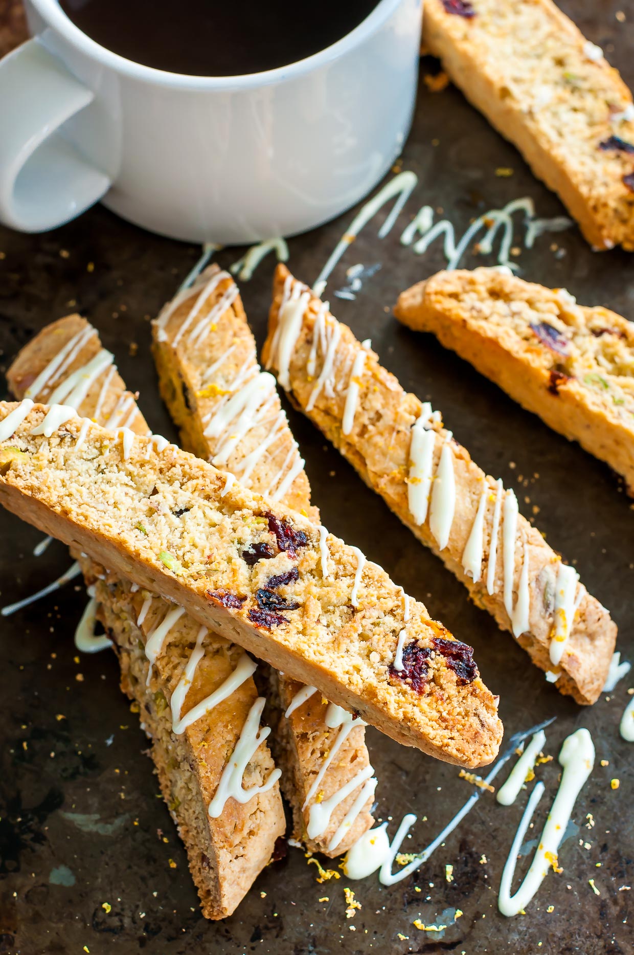 White Chocolate Cranberry Pistachio Biscotti with cup of coffee on baking sheet