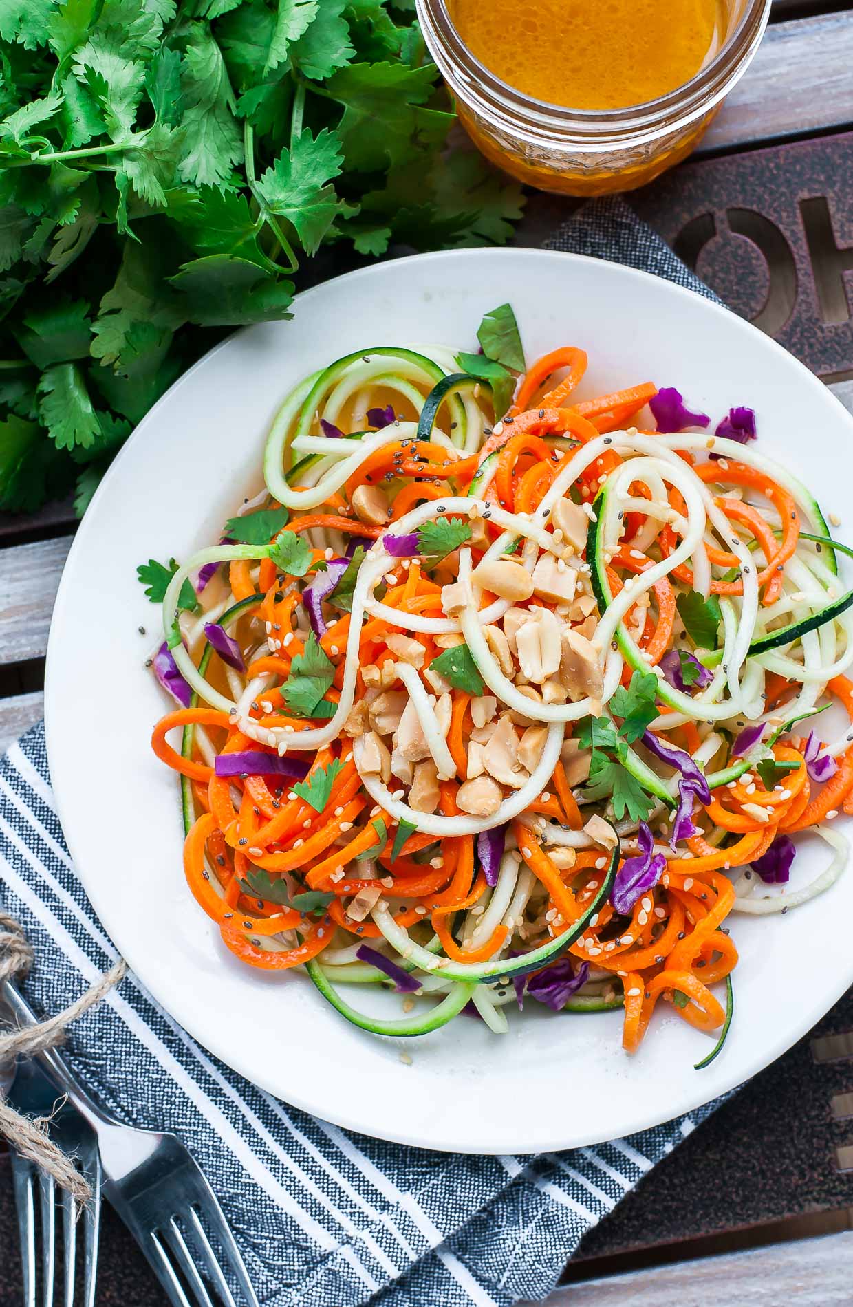 Spiralized Thai Zucchini Noodle Salad with Sriracha Dressing because, YUM! This gorgeous gluten-free salad features a medley of colorful veggies and is topped with peanuts, cilantro, and a tasty homemade dressing.