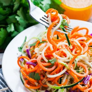 Spiralized Thai Zucchini Noodle Salad with Sriracha Dressing because, YUM! This gorgeous gluten-free salad features a medley of colorful veggies and is topped with peanuts, cilantro, and a tasty homemade dressing.