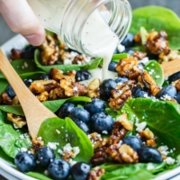 Lemon poppyseed dressing poured over blueberry spinach salad