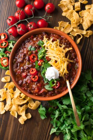 Black Bean Quinoa Chili topped with cheese, sour cream, jalapeño peppers, and cilantro