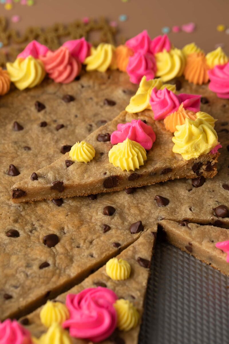 Slice of Chocolate Chip cookie Cake with vanilla frosting on top