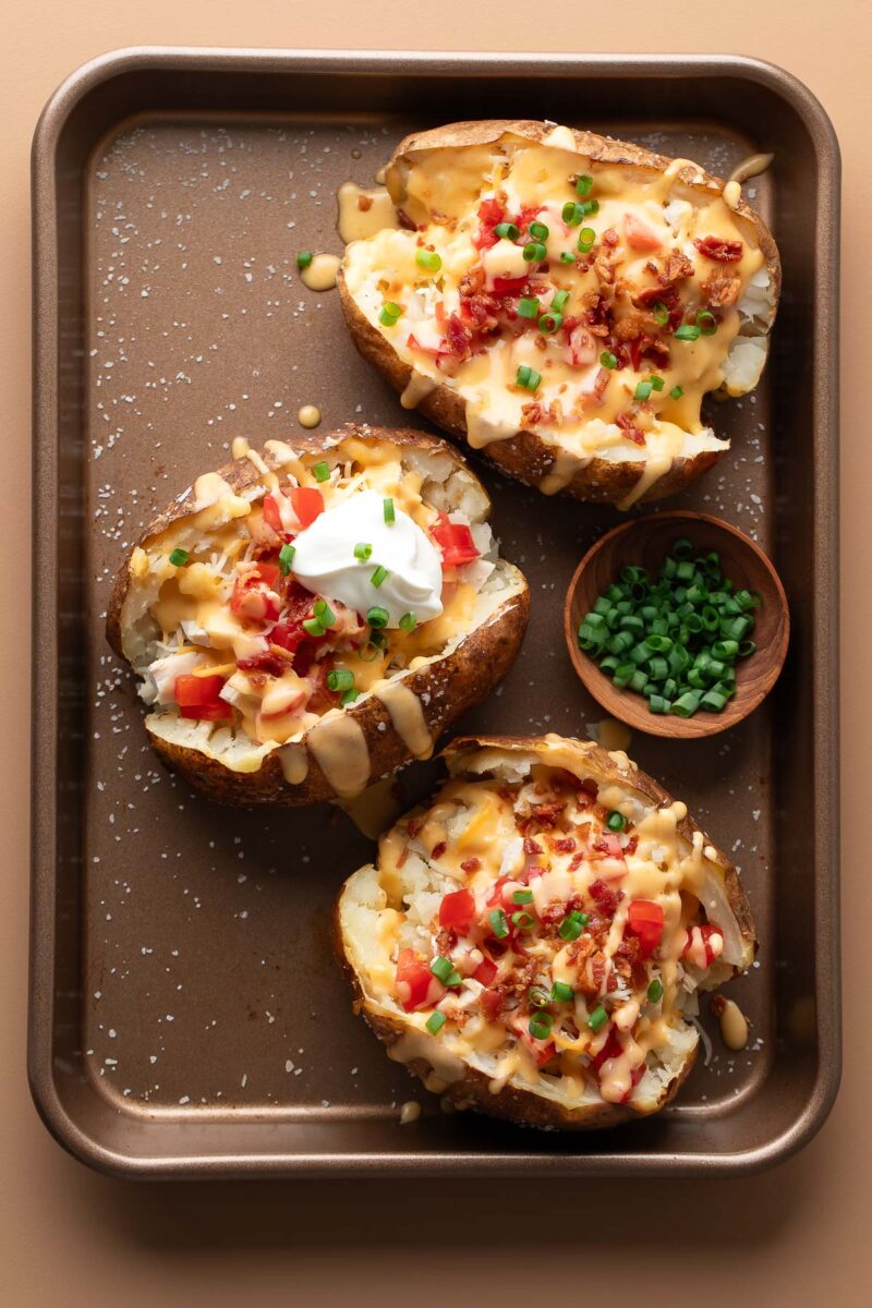 baked russet potatoes stuffed with rotisserie chicken, tomatoes and cheese and topped with scallions, cheese sauce, sour cream, cheese sauce and sour cream