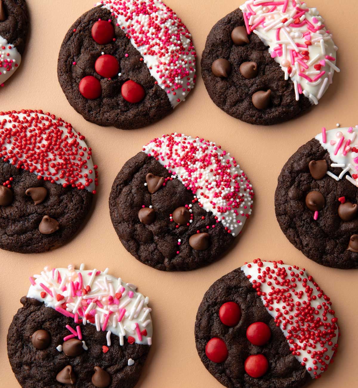 assorted chocolate cookies with chocolate chips dipped in white chocolate and decorated with sprinkles