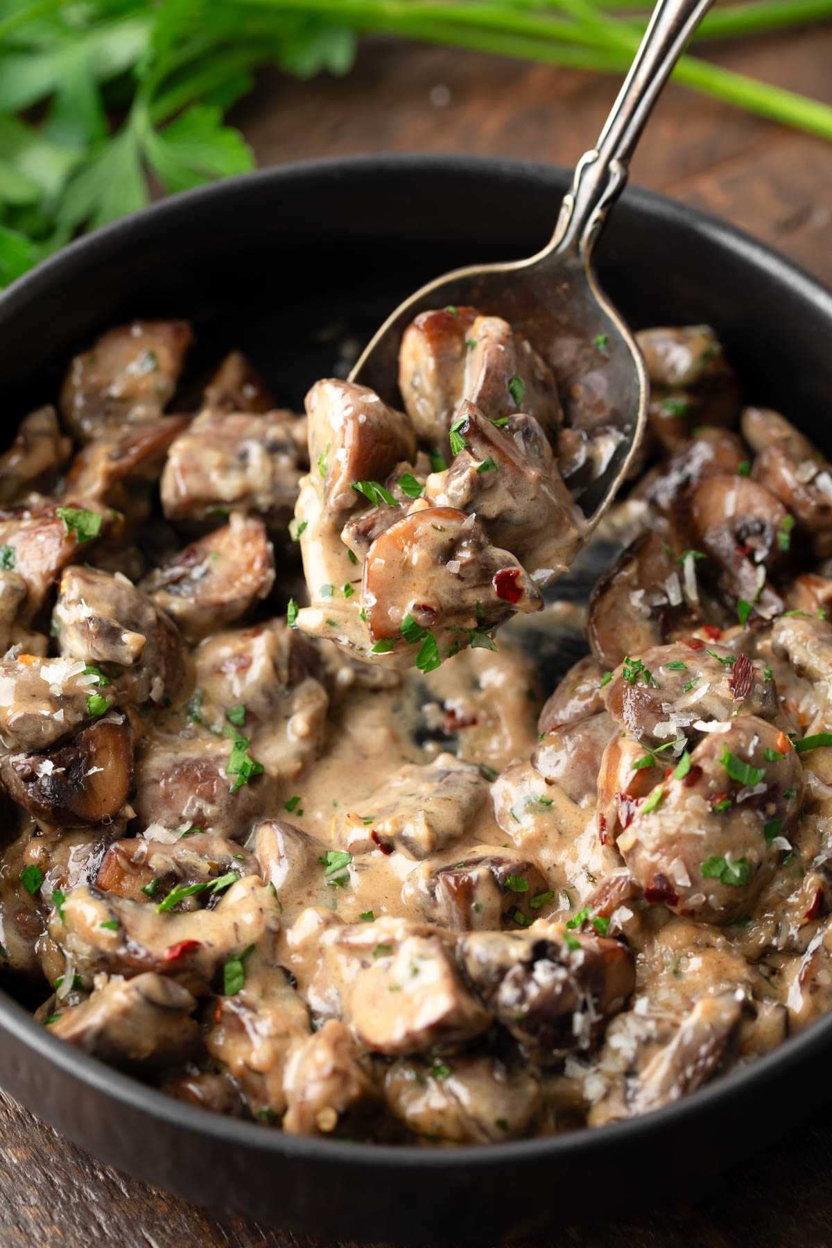 Creamy Garlic Mushrooms in a cast iron skillet with red pepper flakes and parsley