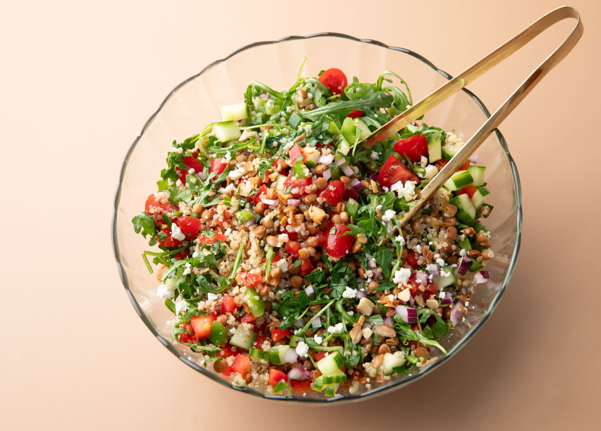 Mediterranean Lentil Salad in a glass serving bowl with serving tongs