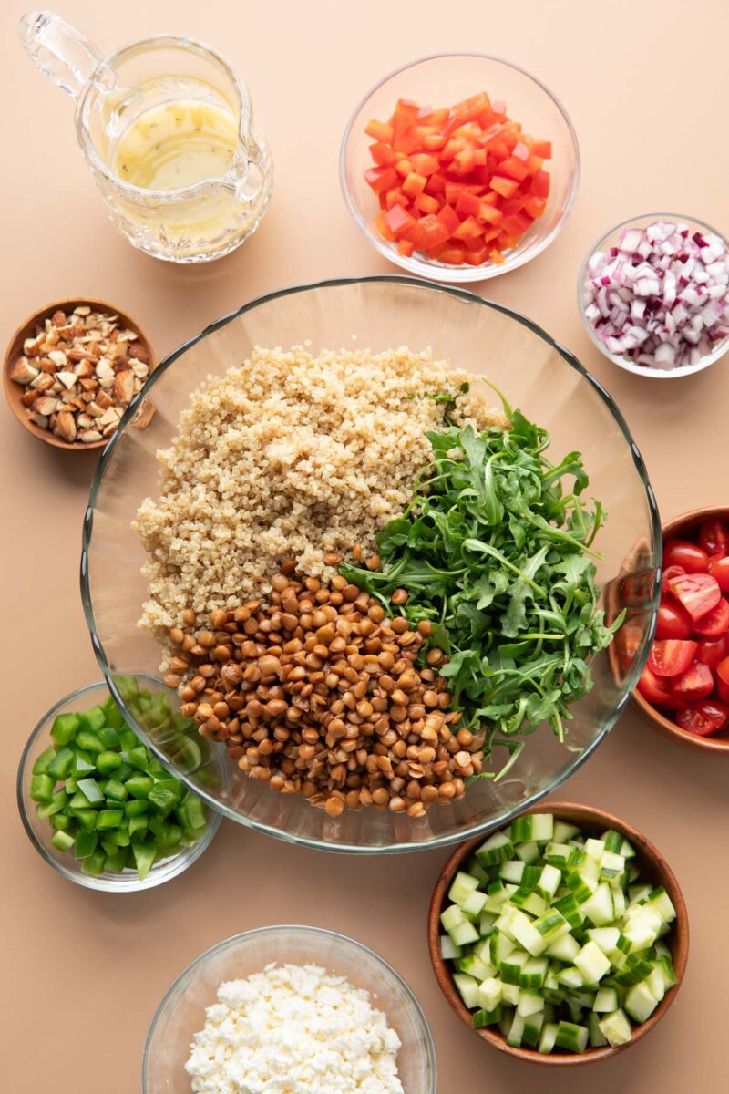 lentil arugula quinoa salad with fresh vegetables, cheese, nuts, and dressing for topping