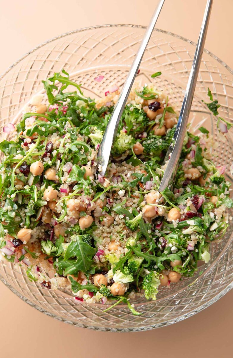 Quinoa Arugula Salad tossed in a glass serving bowl 