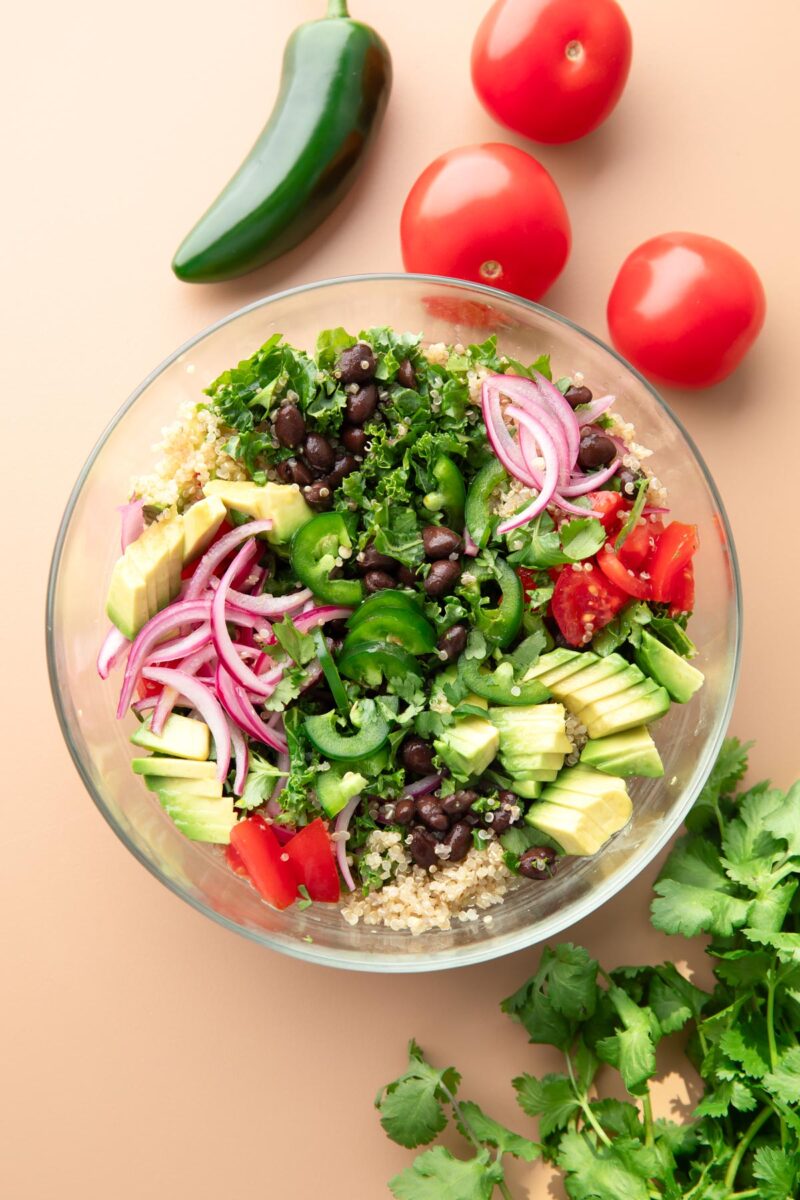quinoa bowls with kale, avocado, tomatoes, pickled red onions, black beans, and jalapeno peppers,