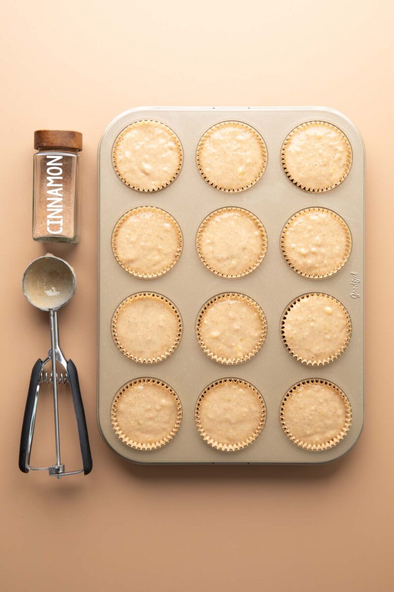 banana applesauce muffin batter portioned into parchment cup lined muffin tin