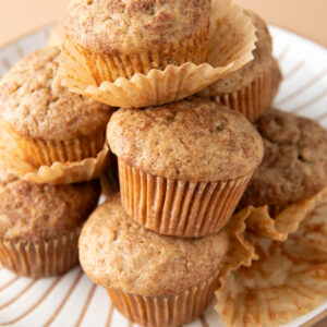 several baked banana muffins stacked on a serving plate